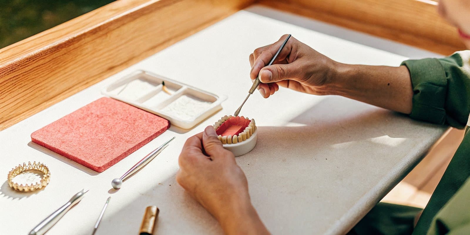 A dental technician's hands shaping a custom restoration at the in-house laboratory bench